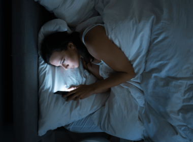 kobieta wysyła życzenia na dobranoc przez telefon z łóżka