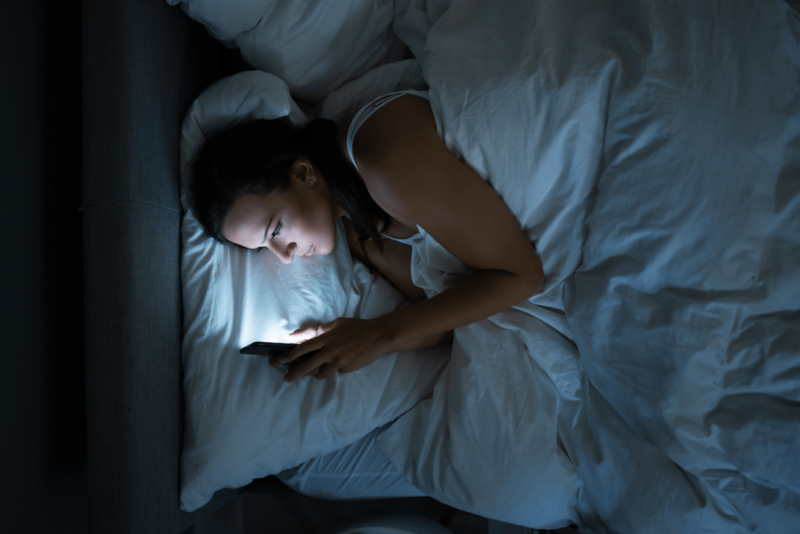 kobieta wysyła życzenia na dobranoc przez telefon z łóżka